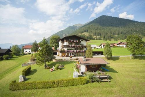 a large house in a field with mountains in the background at Gästehaus Bergland in Berwang