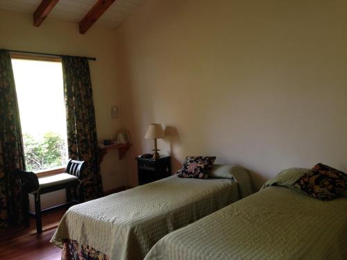 a bedroom with two beds and a window and a chair at Los Abetos B&B 1 in El Bolsón