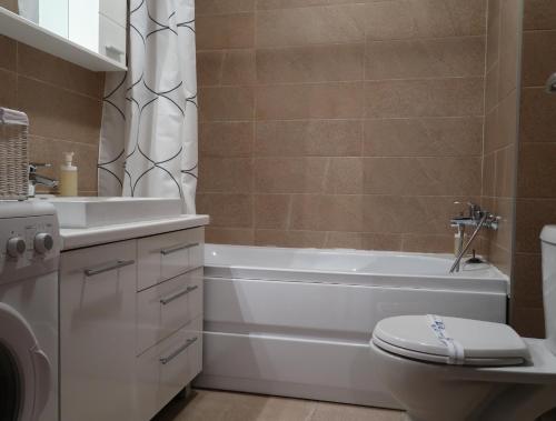 a bathroom with a tub and a toilet and a sink at Orange Onix Apartaments in Bucharest