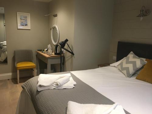 a bedroom with a bed and a desk with a mirror at The Galleon Inn in Fowey