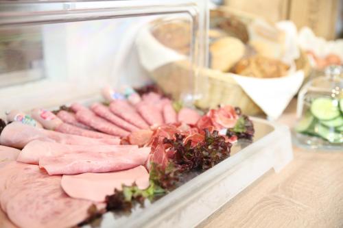 a tray of ham and other meats on a counter at Hotel Pilar Garni in Cologne