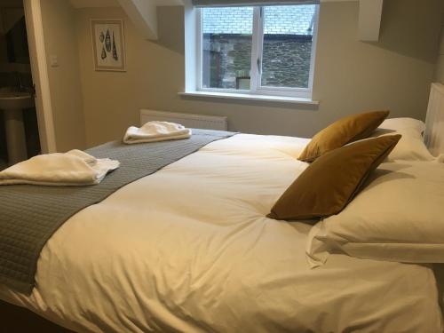 a large white bed with two pillows and a window at The Galleon Inn in Fowey