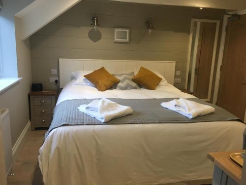 a bedroom with a large bed with two towels on it at The Galleon Inn in Fowey