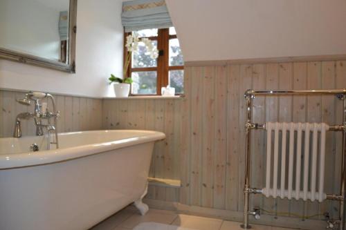 ein Badezimmer mit einer Badewanne, einem Fenster und einem Heizkörper in der Unterkunft Siabod Luxury Cottage in Betws-y-coed