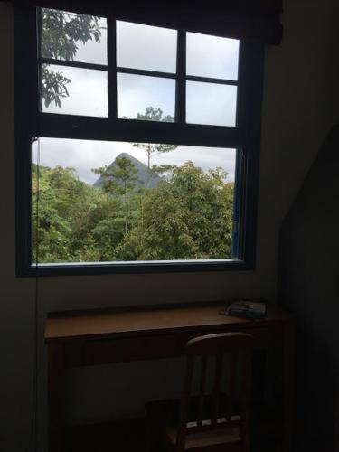 a window in a room with a wooden table and a desk at Pousada Quinta das Nascentes in Petrópolis