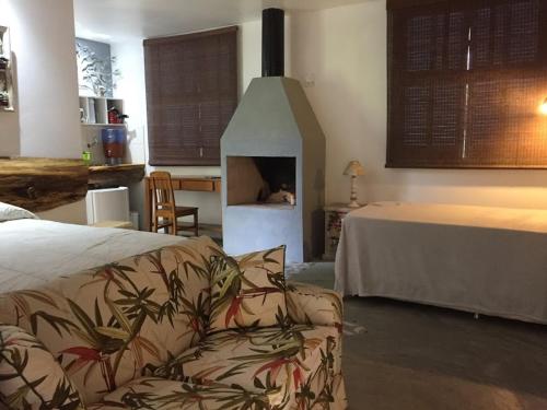 a room with a fireplace with a couch and a bed at Pousada Quinta das Nascentes in Petrópolis