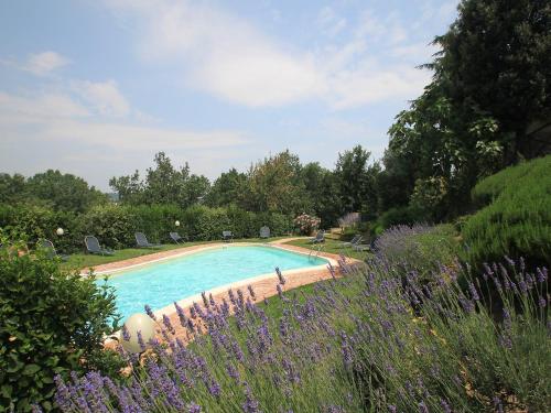 uma piscina num jardim com flores roxas em Apartment Borgo Monticelli-19 by Interhome em Castiglione della Valle