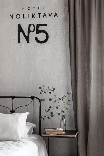 a bedroom with a bed and a sign on the wall at Noliktava No 5 in Kuldīga