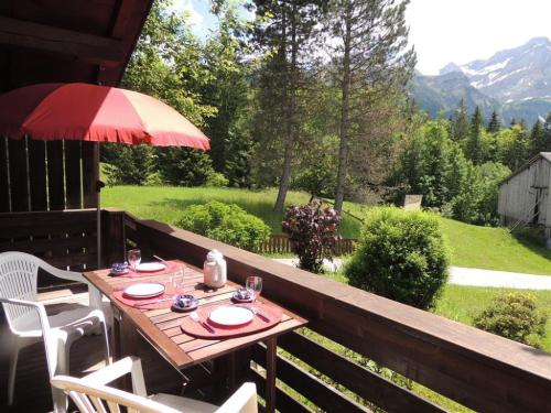 een tafel en stoelen op een veranda met een parasol bij Apartment Minnehaha- Chalet by Interhome in Lauenen