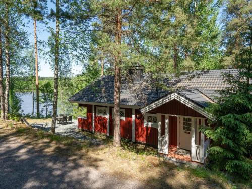 a small red house with a garage in the woods at Holiday Home Satakieli by Interhome in Hirsjärvi