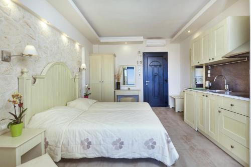 a bedroom with a large white bed and a kitchen at Frini Studios in Plomarion