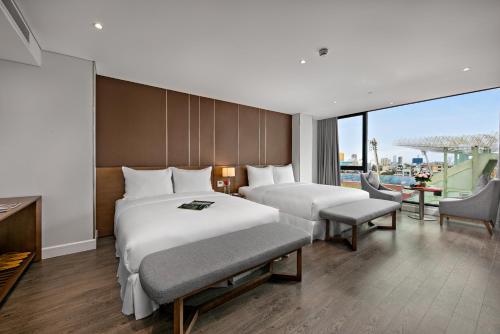 ダナンにあるAVORA Boutique Hotelのベッド2台とバルコニーが備わるホテルルームです。