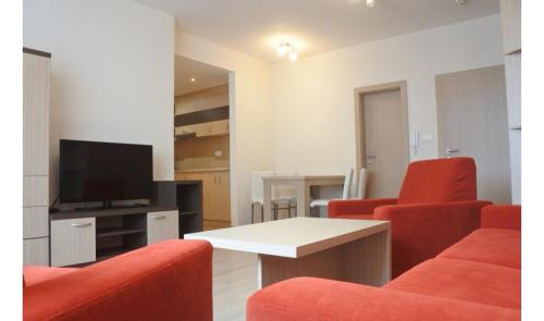 a living room with red chairs and a television at Apartmán v Starej Lesnej s balkónom in Stará Lesná