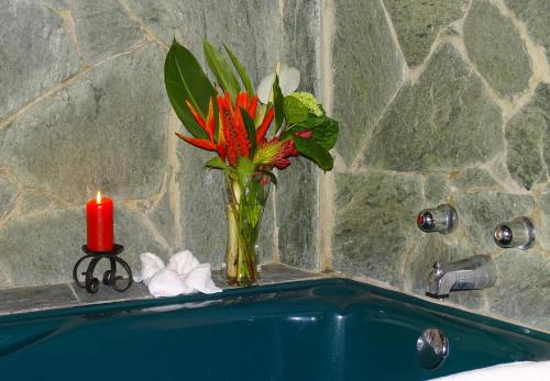a vase of flowers on a bathroom sink with a candle at Casa Divina Eco Lodge in Mindo
