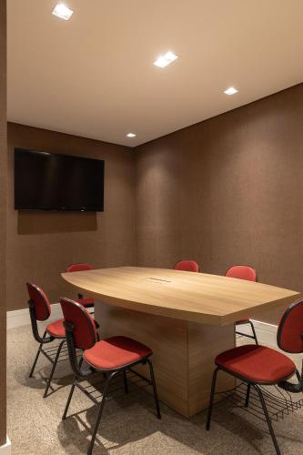 a conference room with a table and red chairs at Hotel Heritage in Sao Paulo