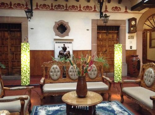 a lobby with chairs and a table with a vase at Hotel Los Escudos in Pátzcuaro