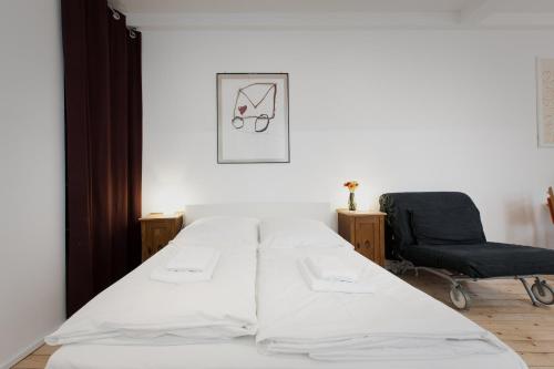 a white bed in a room with a chair at Mini-Loft (KB7) in Berlin