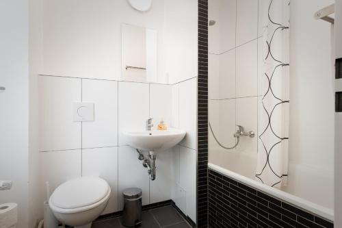 a white bathroom with a toilet and a sink at Mini-Loft (KB7) in Berlin