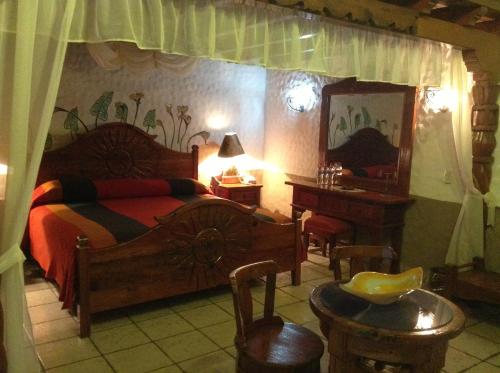 a bedroom with a bed and a table and a mirror at Hotel Los Escudos in Pátzcuaro