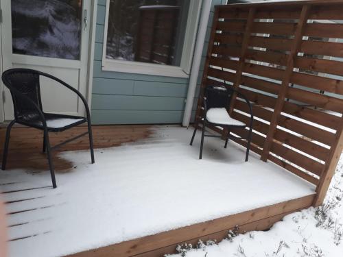 two chairs sitting on a porch covered in snow at Vuokatti Slope Suite in Vuokatti