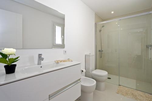 e bagno bianco con servizi igienici e doccia in vetro. di Marieta Bajos a Colonia Sant Jordi