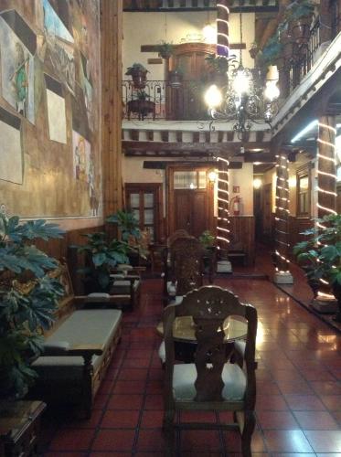 a lobby with chairs and plants in a building at Hotel Los Escudos in Pátzcuaro