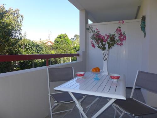 a white table with a vase of flowers on a balcony at Apartment Selvia Quetia by Interhome in Ondres