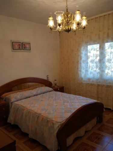 a bedroom with a bed with a chandelier and a window at Casa naranja in Teruel