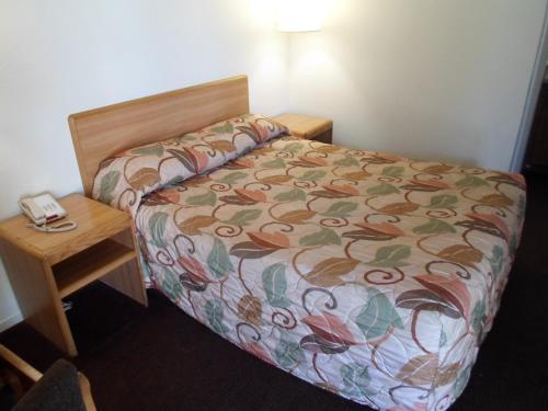 Un dormitorio con una cama y un teléfono en una mesa. en EZ 8 Motel Newark, en Newark