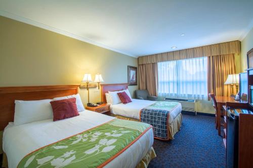 a hotel room with two beds and a desk at Anchorage Inn and Suites in Portsmouth