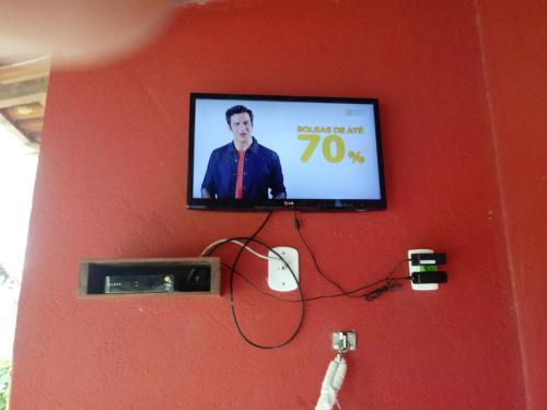 uma televisão de ecrã plano numa parede vermelha em Condomínio Canaã Cumuruxatiba em Cumuruxatiba