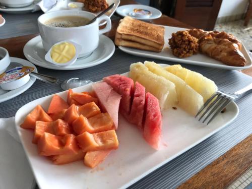 a plate of fruit on a table with a cup of coffee at Villa Ekabo in Cotonou