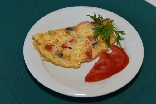 a white plate with a slice of pizza and a tomato at Villa Konak Hotel in Kusadası