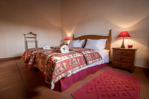 a bedroom with a bed with a red blanket and a night stand at Casas da Piedade in Azinhaga