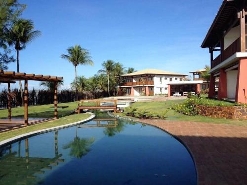 a house with a swimming pool in front of a building at Apartamento beira-mar no Bali Bahia in Itacimirim