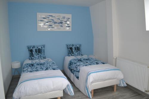 twee bedden in een kamer met blauwe muren bij Gîte & SPA Les Hirondelles de 2 à 8 personnes in Arnèke