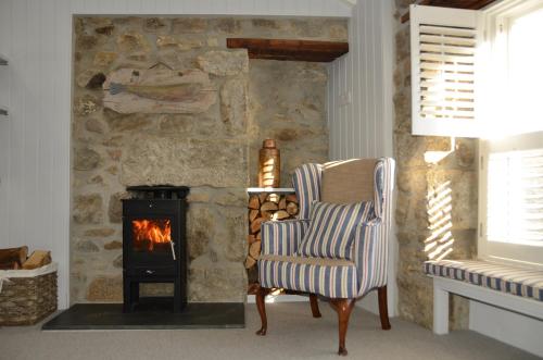 a living room with a chair and a fireplace at Sunny Corner in Mousehole