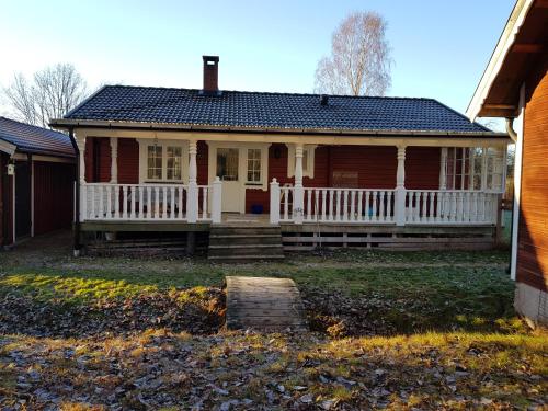 una casa con portico e recinzione bianca di Lilla Huset Oleby a Torsby