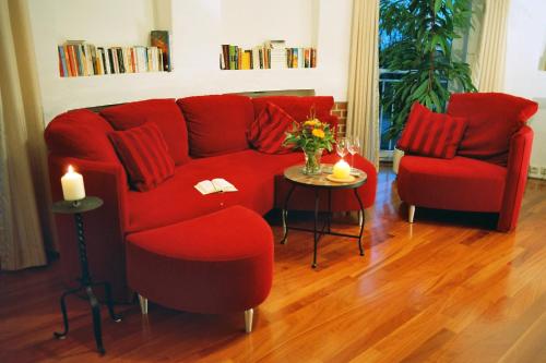 a living room with a red couch and two chairs at Wasserturm Cuxhaven in Cuxhaven