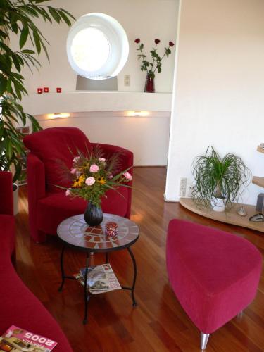 a living room with a red chair and a table with flowers at Wasserturm Cuxhaven in Cuxhaven