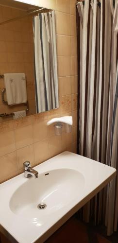 un lavandino in bagno con specchio e tenda per la doccia di Jämtkrogen Hotell a Bräcke