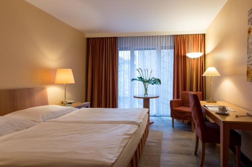 ベルリンにあるリレクサ ホテル シュトゥットガルター ホフのベッド、デスク、椅子が備わるホテルルームです。