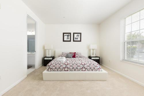 a white bedroom with a bed and two lamps at Wonderful Vacation Apartment with Balcony at Vista Cay VC5025-103 in Orlando