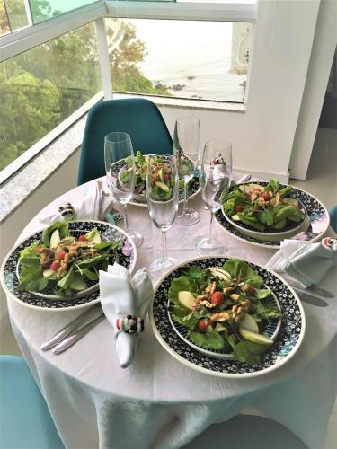 a table with three plates of food and wine glasses at Apartamento Studio Superior com vista da BIG Wheel in Balneário Camboriú