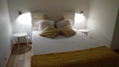 a bedroom with a bed with pillows and two tables at Casa da Corisca in Vila Franca do Campo
