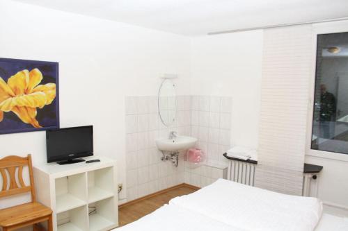 een badkamer met een bed, een wastafel en een televisie bij Hotel Schwaferts in Wuppertal