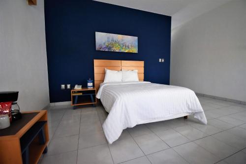 a bedroom with a large bed with a blue wall at Hotel México Inn Express in Salamanca
