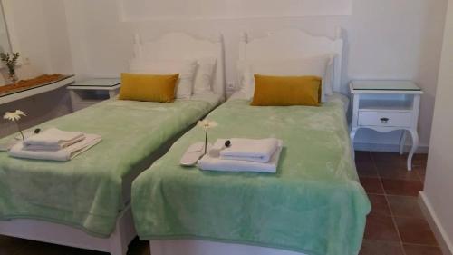 duas camas num quarto com lençóis verdes e toalhas em NN Luxury Room near Athens Airport em Spata