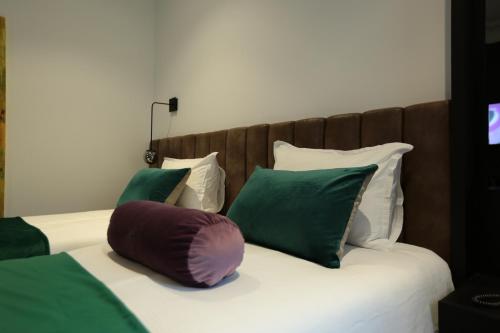 a bed with green and white pillows on it at Hotel Rubis in Ferizaj