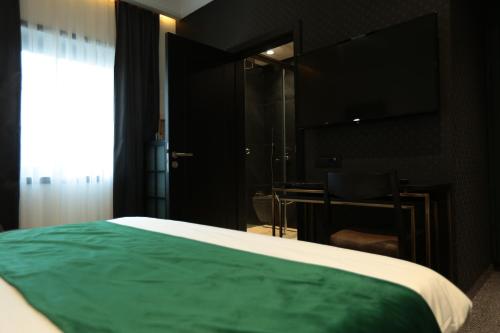a bedroom with a green bed and a desk at Hotel Rubis in Ferizaj